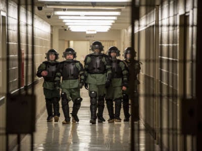 An Office of Enforcement and Removal Operations Special Response Team walks through a detention facility in riot gear.