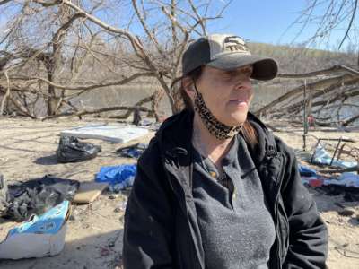 Terri Domer visits the riverside encampment in Cedar Rapids, where she weathered last August's derecho.