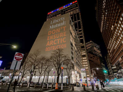 the words "LIBERTY MUTUAL: DON'T ENSURE ARCTIC DESTRUCTION" are projected onto the side of a building