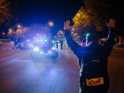 A protester holds up his hands in front of a line of police officers
