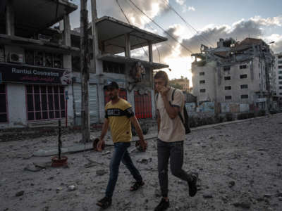 People walk past destroyed commercial building and Gaza health care clinic following an Israeli airstrike on the upper floors of a commercial building near the Health Ministry in Gaza City on May 17, 2021, in Gaza City, Gaza.