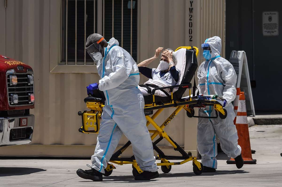 A elderly person is wheeled away in a gurney