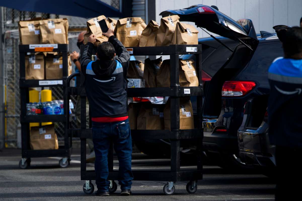 An Amazon.com Inc. delivery driver scans bags of groceries while loading a vehicle outside of a distribution facility in Redondo Beach, California.
