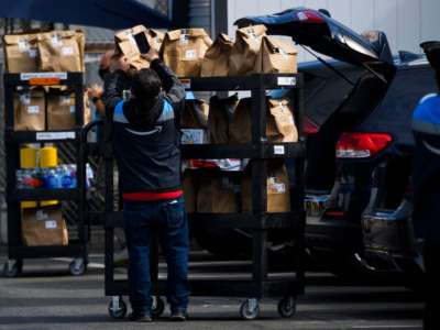 An Amazon.com Inc. delivery driver scans bags of groceries while loading a vehicle outside of a distribution facility in Redondo Beach, California.