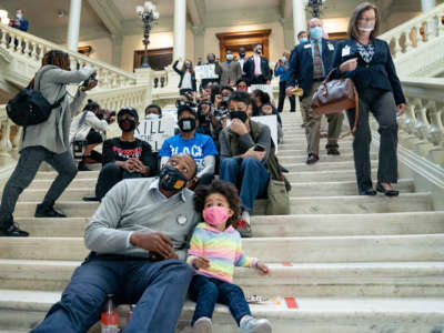 A masked dad talks to his masked child during a protest