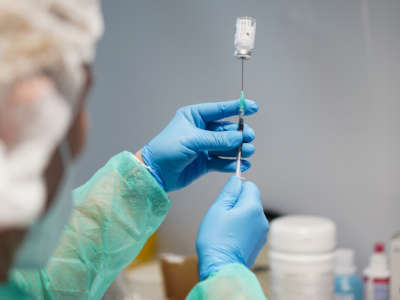 A medical worker draws up a syringe of the vaccine