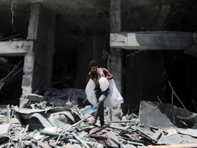 A man carries bags out of a destroyed building