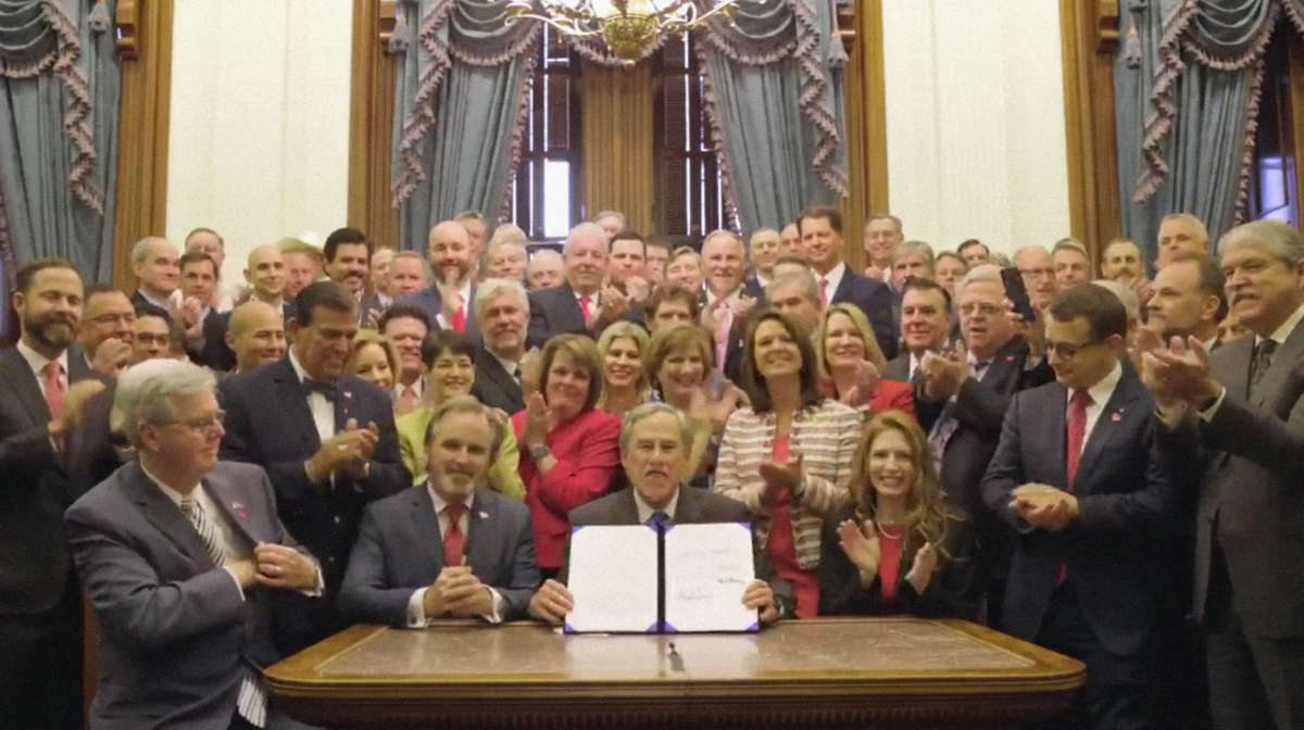 Texas Gov. Greg Abbott holds up the signed "heartbeat ban" on abortion at a signing ceremony on May 19, 2021.