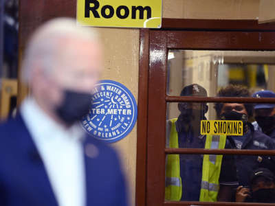 Three workers watch Joe Biden from behind a closed door