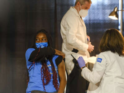 A woman rolls up her sleeve to recieve The Vaccine