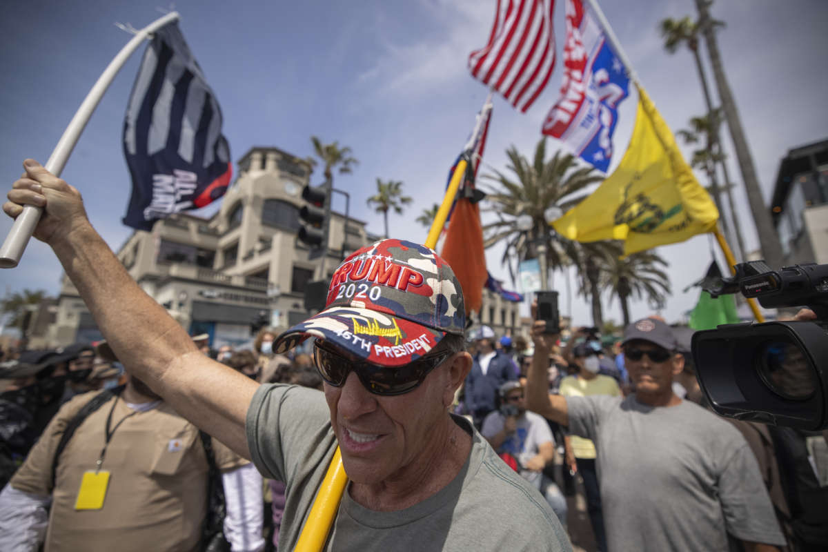 An Evangelical Christian Donald Trump supporter carries flags at the site of a "White Lives Matter" rally on April 11, 2021, in Huntington Beach, California.