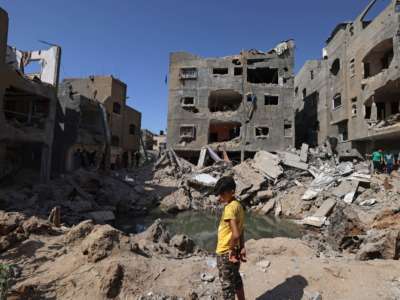 A Palestinian child stands amid the rubble of buildings, destroyed by Israeli strikes, in Beit Hanun in the northern Gaza Strip on May 21, 2021.