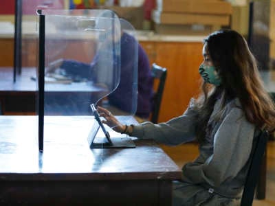 Senior student Ariana Diaz with a plexiglass barrier in the art classroom of Art 2 teacher Patty Steponovich as students return to in-person instruction at St. Anthony Catholic High School in Long Beach on March 24, 2021.