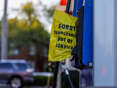 A yellow bag reading "SORRY; TEMPORARILY OUT OF SERVICE" covers a gas pump