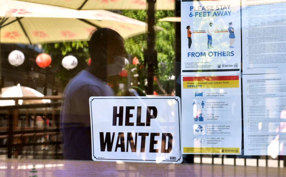 A "Help Wanted" sign is posted beside Coronavirus safety guidelines in front of a restaurant in Los Angeles, California, on May 28, 2021.