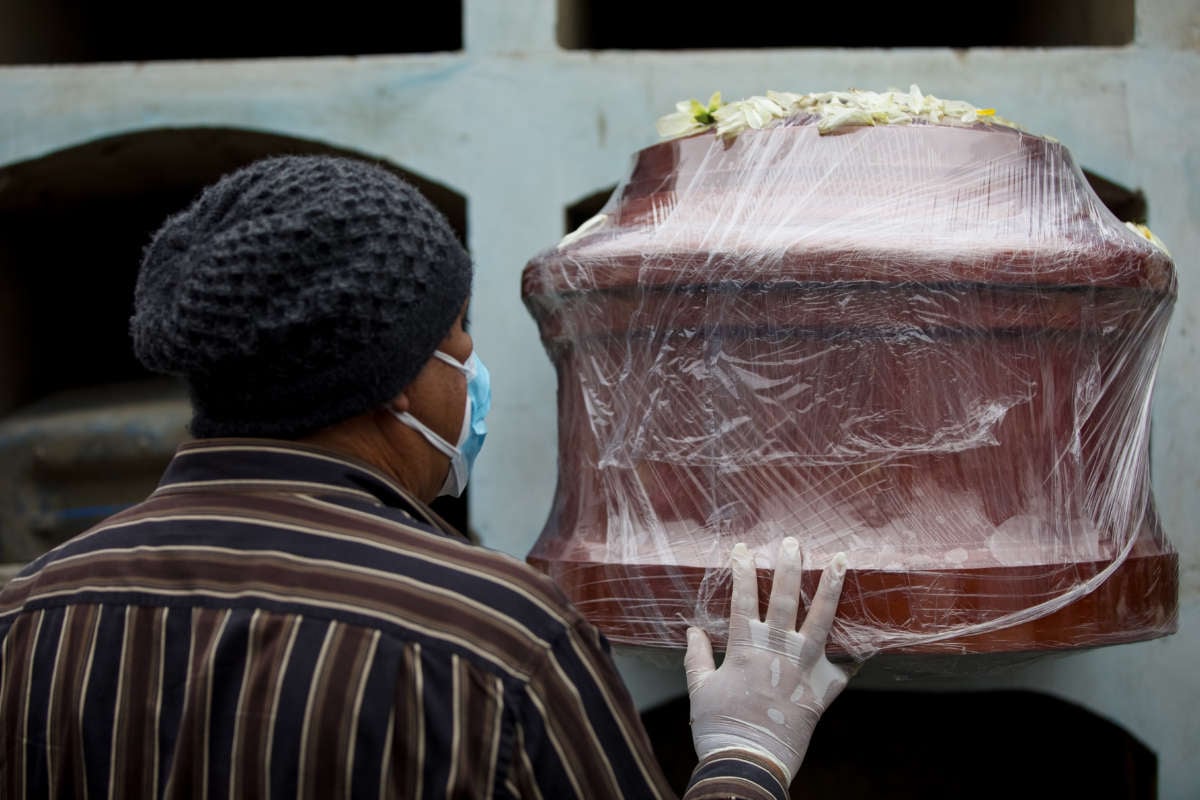 A man touches the coffin of his relative who died of COVID-19 on June 1, 2021, in Lima, Peru.
