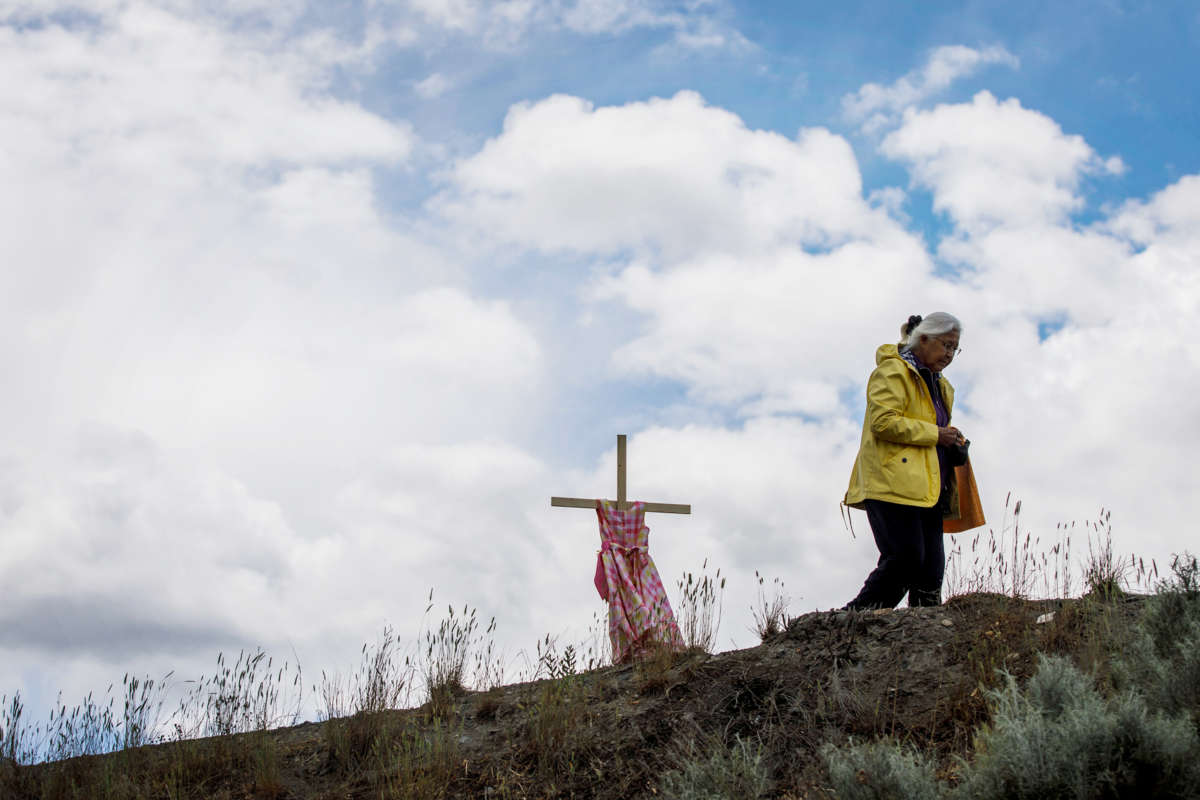 A woman walks away from a cross with a girl's dress draped across it