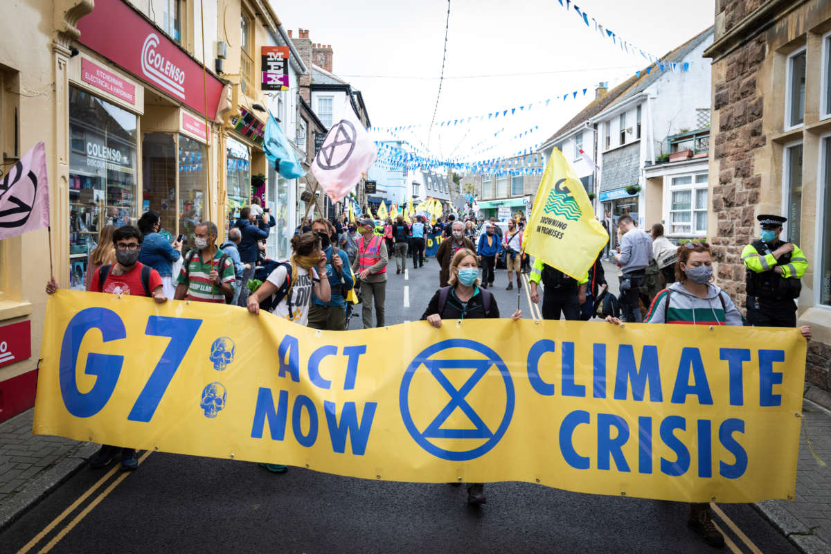 Protesters march with a banner through St. Ives village near where delegates are meeting for the 47th G7 in the United Kingdom, on June 11, 2021.