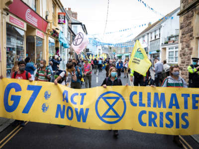 Protesters march with a banner through St. Ives village near where delegates are meeting for the 47th G7 in the United Kingdom, on June 11, 2021.