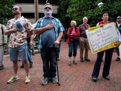 People hold up signs during a rally against "critical race theory" (CRT) being taught in schools at the Loudoun County Government center in Leesburg, Virginia, on June 12, 2021.