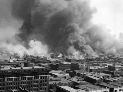 an aerial view of the Tulsa Race Riot with smoke billowing up from buildings