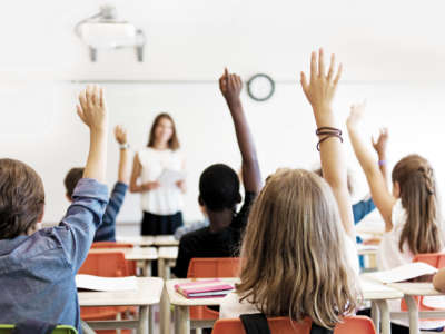 Students in classroom raising hands