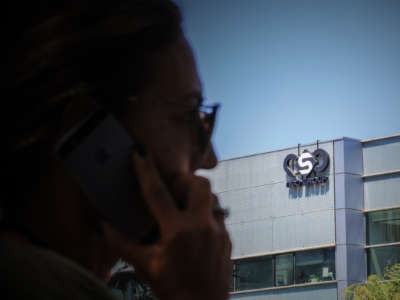 A woman talks on her cell phone in front of the headquarters of an international surveillance service