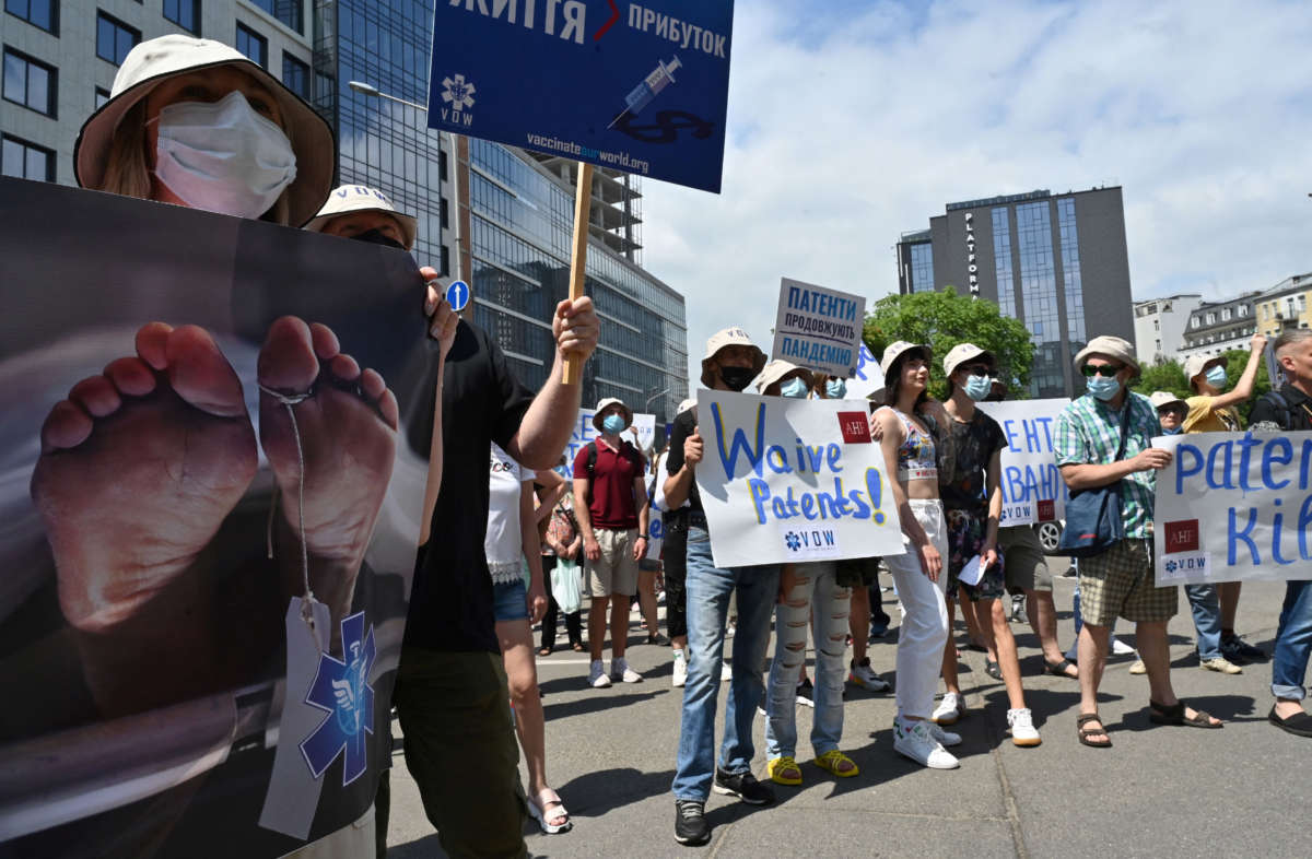 Activists hold placards reading "Patents kill", "Free vaccine" and "Waive patents" during a rally in Kiev, Ukraine, on July 2, 2021.