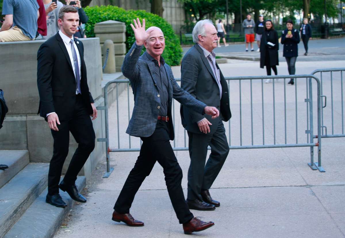 Jeff Bezos waves while crossing the street