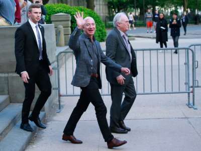 Jeff Bezos waves while crossing the street