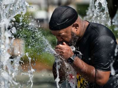 A man cools off in a fountain at the Inner Harbor in Baltimore, Maryland, on June 30, 2021, as a heat wave threatens to make it Baltimore's hottest day of the year.