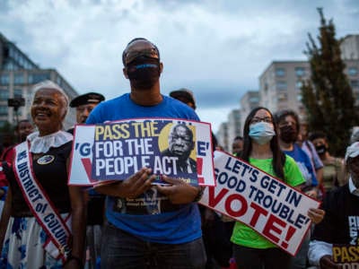 People hold placards with an image of the late Rep. John Lewis during a rally in support of voting rights, at Black Lives Matter Plaza in Washington, D.C., on July 17, 2021.