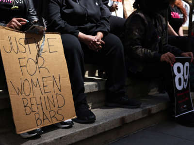 A person at a protest displays a sign reading "JUSTICE FOR WOMEN BEHIND BARS"