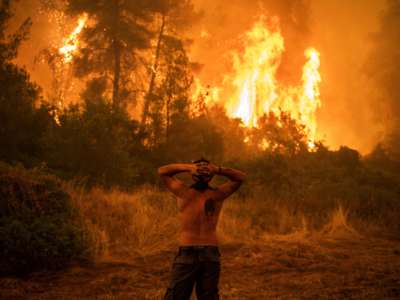 A man looks on in dismay at the burning countryside