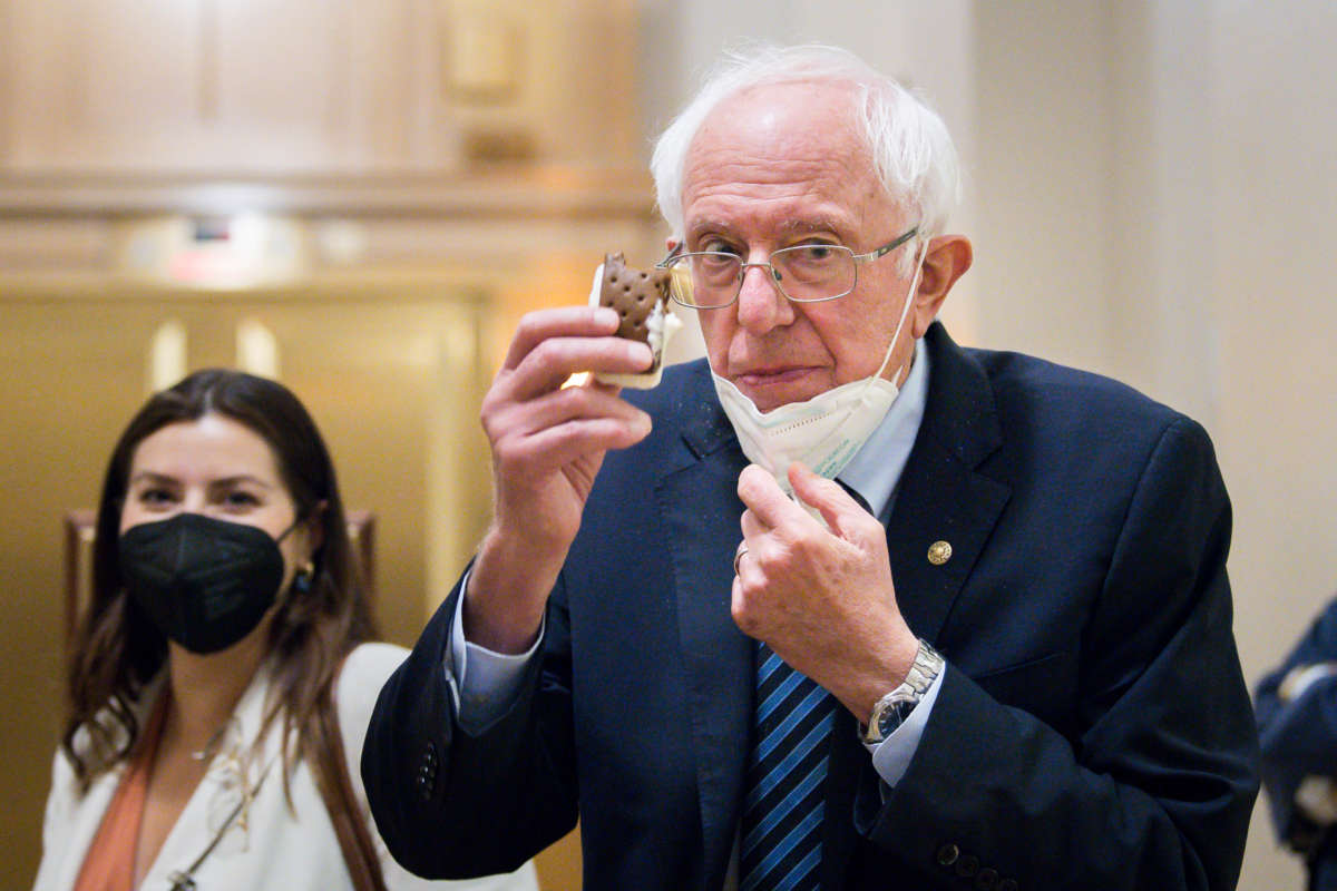Sen. Bernie Sanders (I-Vermont) lowers his mask and holds up an ice cream sandwich while taking a break from the Senate floor budget resolution proceedings on August 10, 2021 in Washington, D.C.