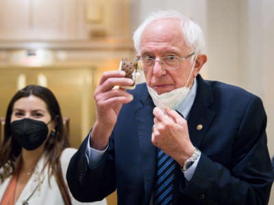 Sen. Bernie Sanders (I-Vermont) lowers his mask and holds up an ice cream sandwich while taking a break from the Senate floor budget resolution proceedings on August 10, 2021 in Washington, D.C.