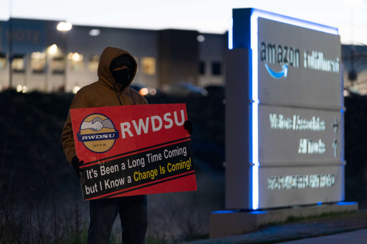 A protester holds up a sign reading "RWDSU: It's been a long time coming but I know a change is coming" during an outdoor protest