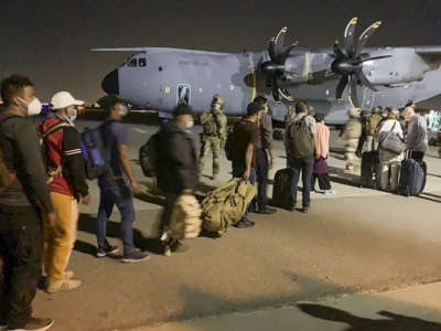 Refugees line up at night to board a plane