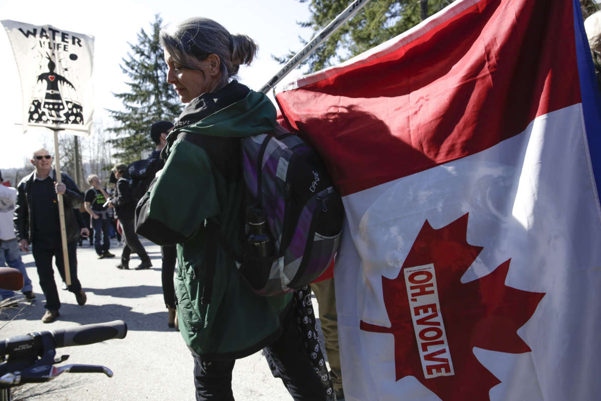 A protester holds a Canadian Flag with the words "OH, EVOLVE" affixed to it