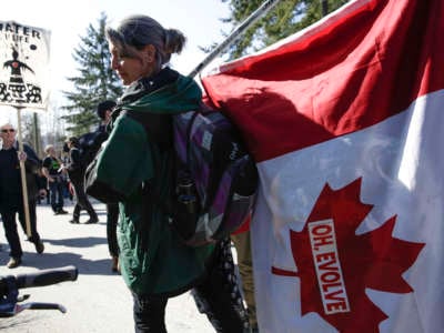 A protester holds a Canadian Flag with the words "OH, EVOLVE" affixed to it