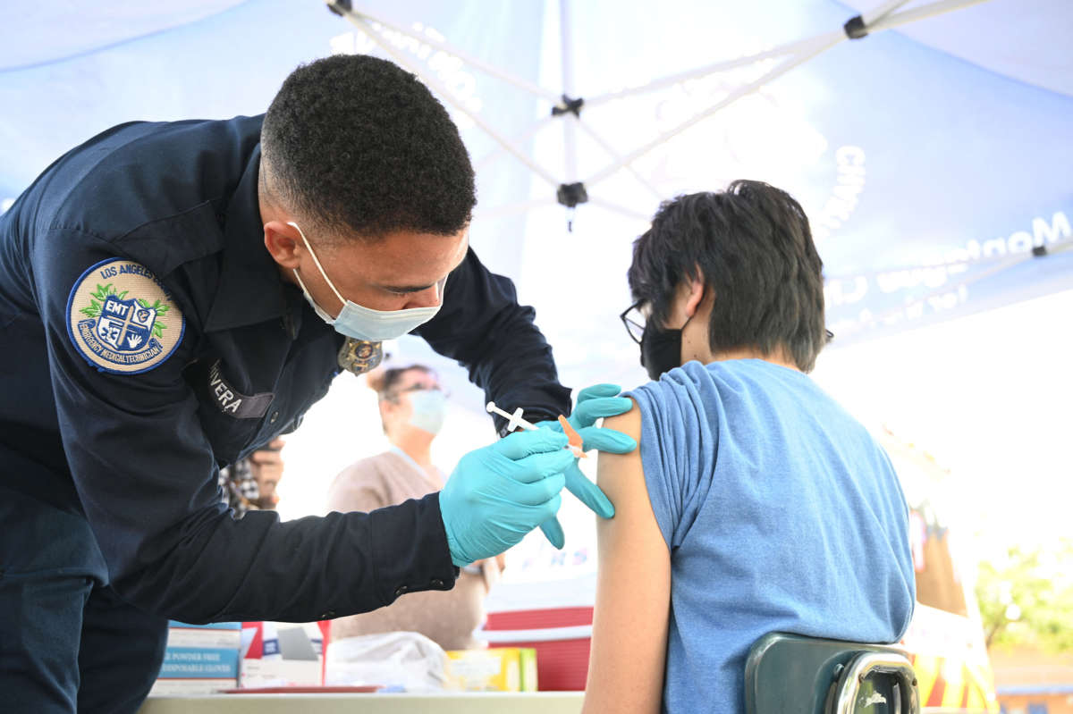 A medical worker injects a teen with the covid vaccine
