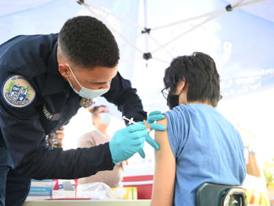 A medical worker injects a teen with the covid vaccine