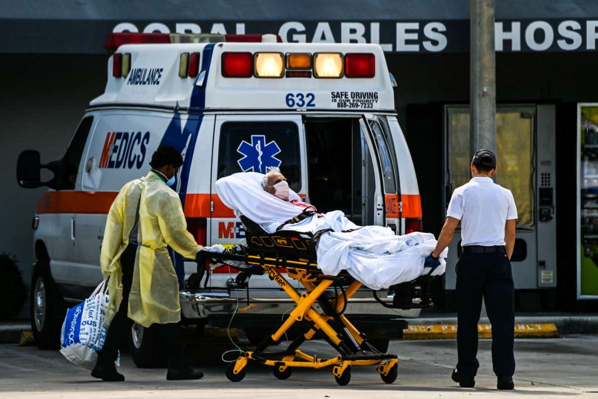 An elderly patient is wheeled from an ambulance to the emergency room on a gurney