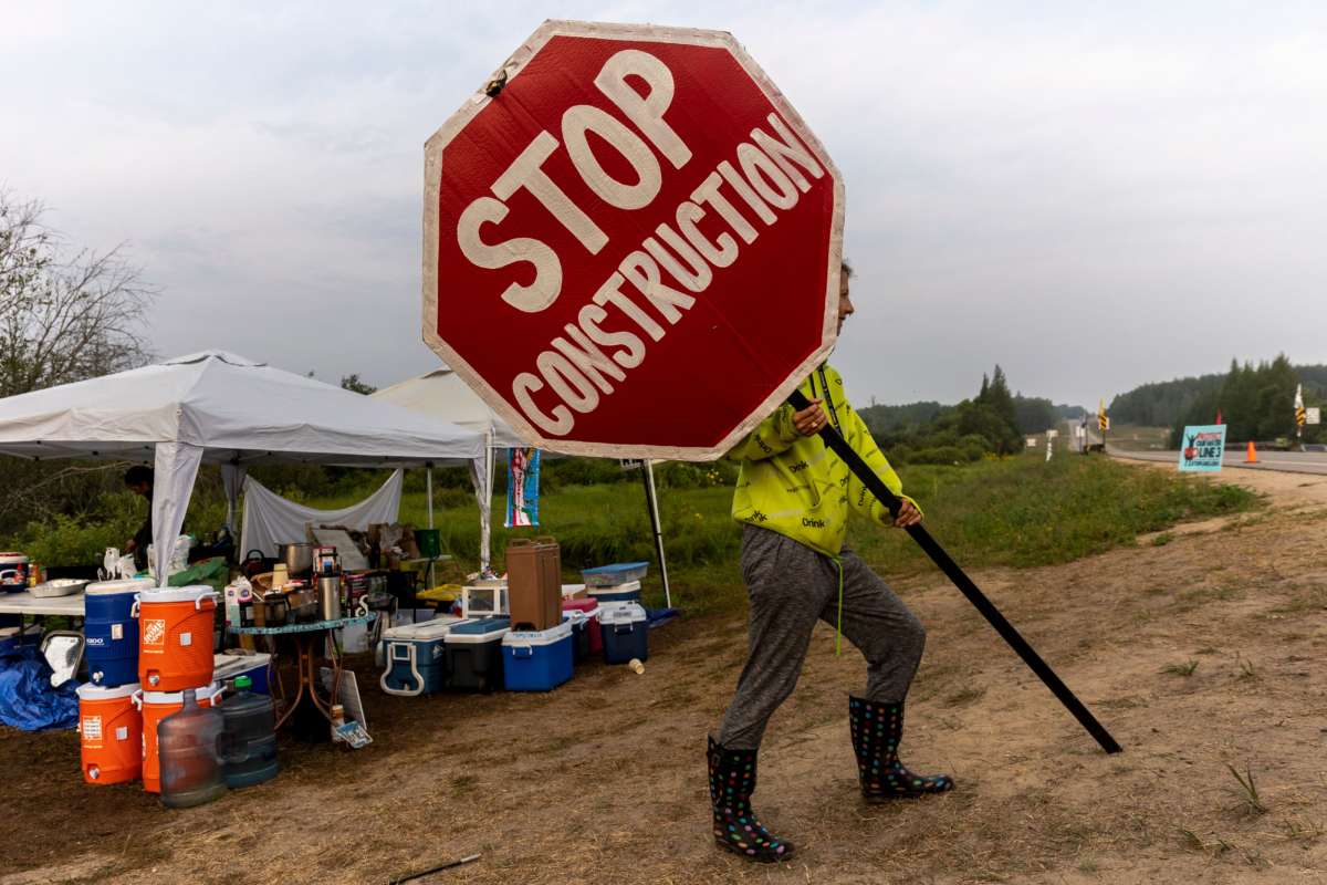 A climate activist holds a sign at the firelight resistance camp near La Salle Lake State Park in Solway, Minnesota, on August 7, 2021.