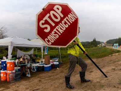 A climate activist holds a sign at the firelight resistance camp near La Salle Lake State Park in Solway, Minnesota, on August 7, 2021.