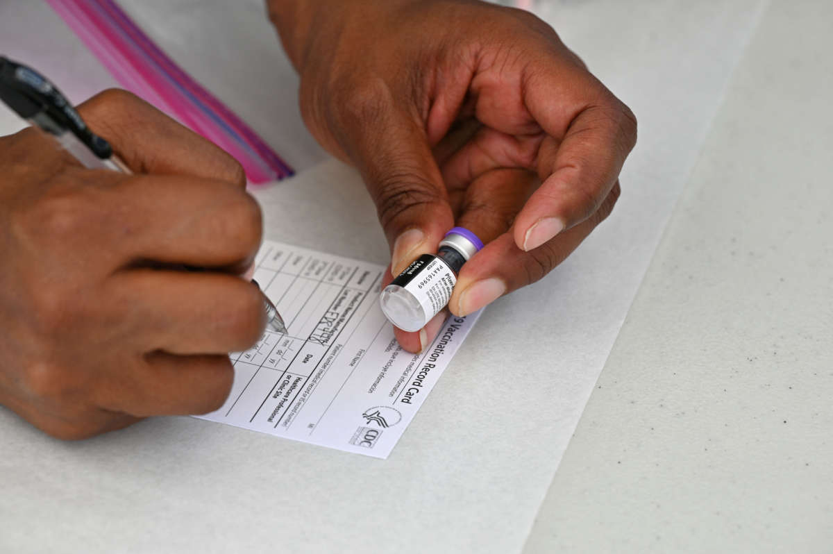 A health care worker fills out a COVID-19 vaccination card at a community event in Los Angeles, California, on August 11, 2021.