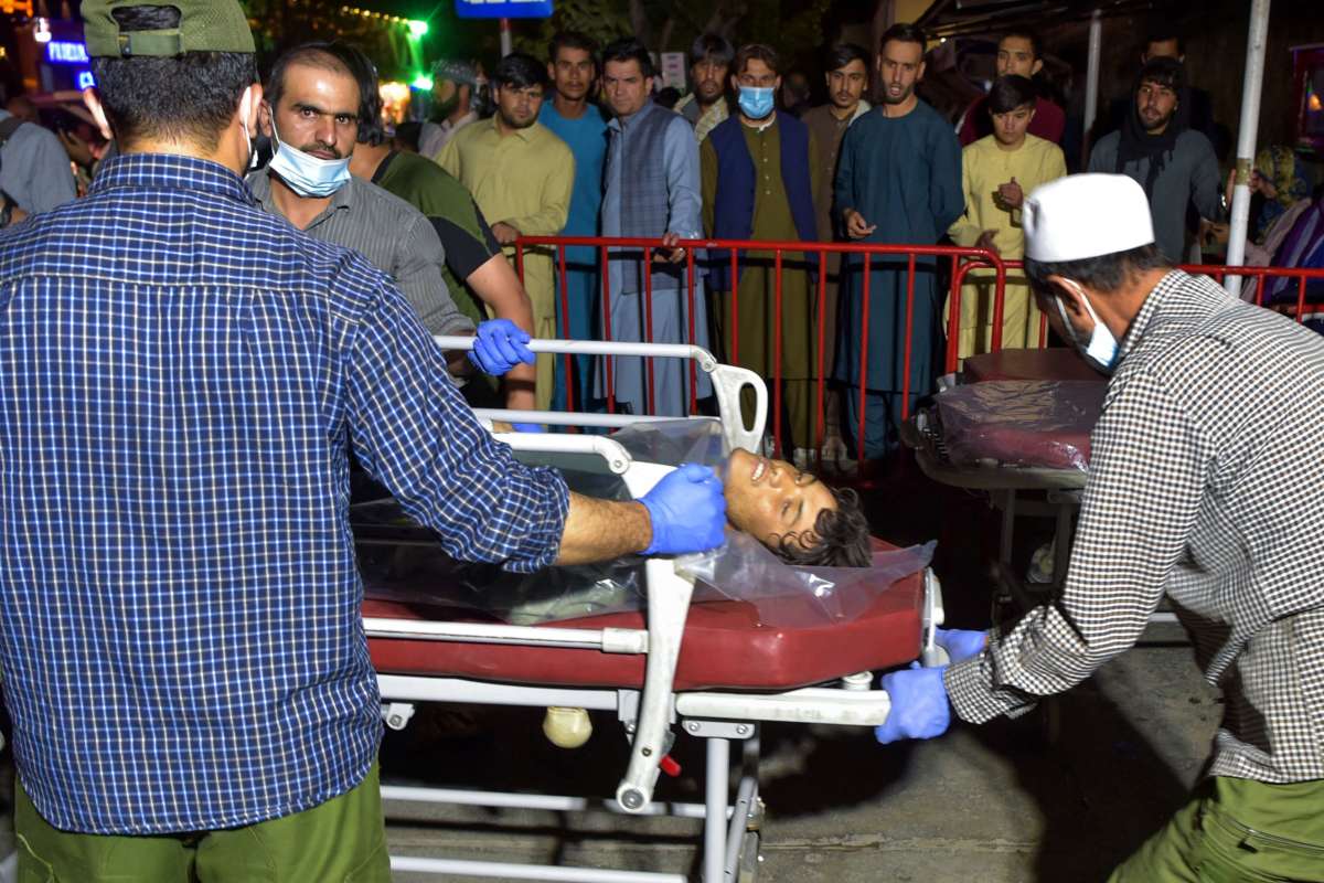 Volunteers and medical staff bring an injured man on a stretcher to a hospital for treatment after two powerful explosions outside the airport in Kabul, Afghanistan, on August 26, 2021.