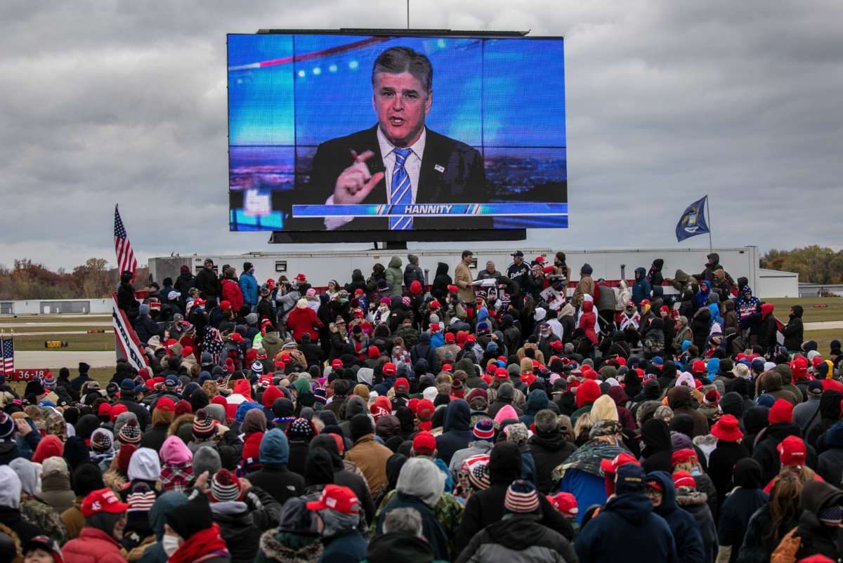 Supporters of then-President Donald Trump watch a video featuring Fox host Sean Hannity ahead of Trump's arrival to a campaign rally at Oakland County International Airport on October 30, 2020, in Waterford, Michigan.