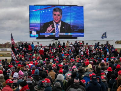 Supporters of then-President Donald Trump watch a video featuring Fox host Sean Hannity ahead of Trump's arrival to a campaign rally at Oakland County International Airport on October 30, 2020, in Waterford, Michigan.