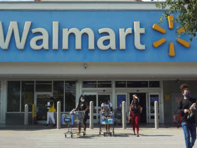People wearing protective masks walk from a Walmart store on May 18, 2021, in Hallandale Beach, Florida.